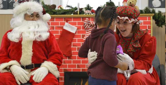 Santa and Mrs. Clause greet a younger student